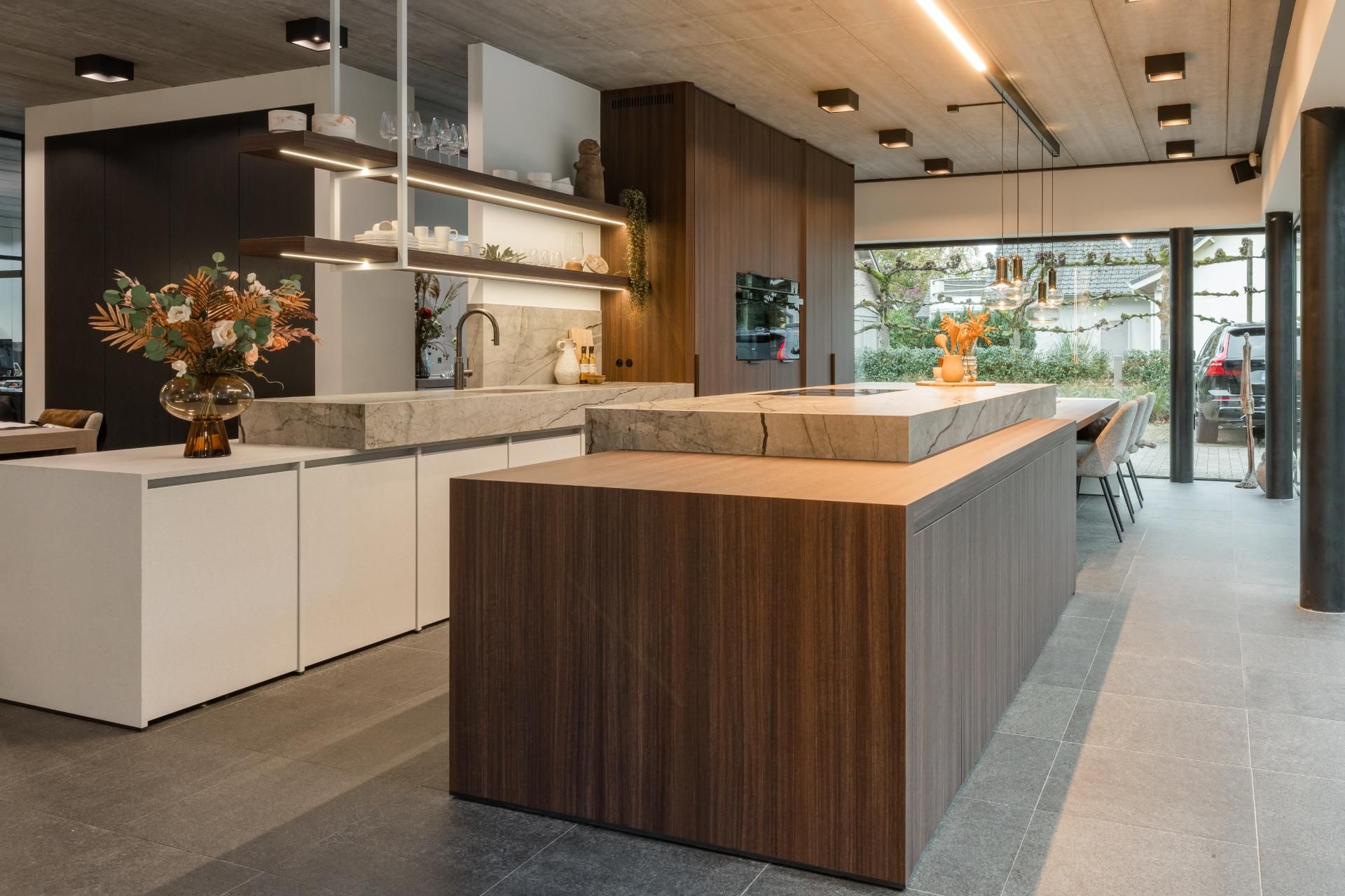 Een moderne keuken met een minimalistisch ontwerp, voorzien van een ruim kookeiland, ingebouwde kasten en hoogwaardige afwerking. De natuurlijke houttinten en het ruime ontwerp maken de keuken tijdloos.