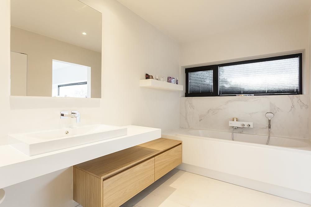 Badkamer op maat van Dorus Coppelmans met een ruim ligbad, marmeren achterwand en houten onderkasten voor een luxueus en duurzaam totaalinterieur.