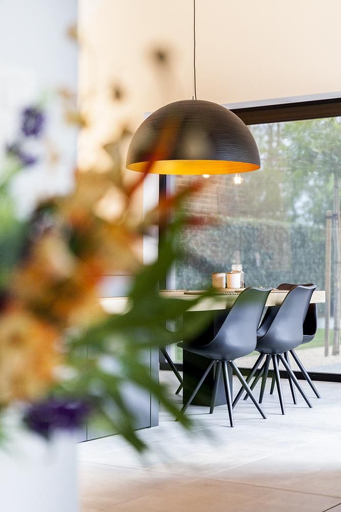 Eethoek op maat door Dorus Coppelmans met zwarte stoelen, houten tafel en een grote hanglamp voor een modern en duurzaam totaalinterieur.