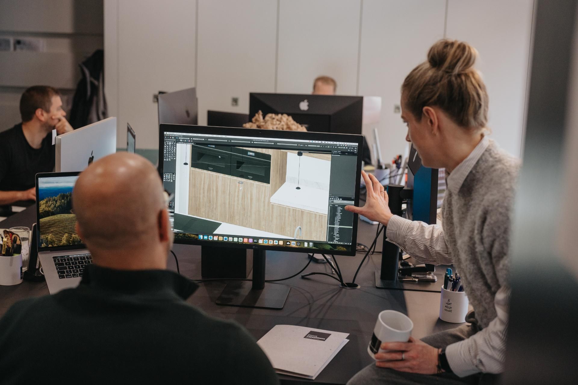Een overlegmoment in een moderne kantooromgeving, waar een ontwerpteam samenwerkt aan interieurideeën. De betrokken en persoonlijke aanpak van een familiebedrijf komt hier naar voren.