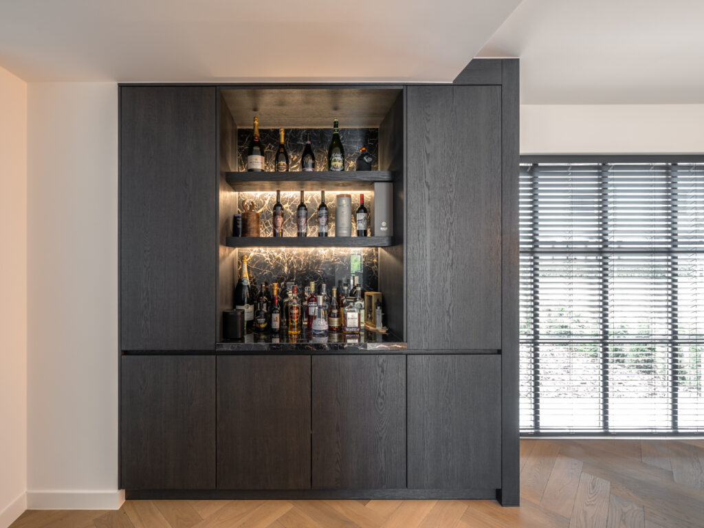luxe keuken in donker hout met barkast en indirecte verlichting